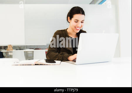 Sorridente ragazza ispanica lavorando sul computer portatile Foto Stock