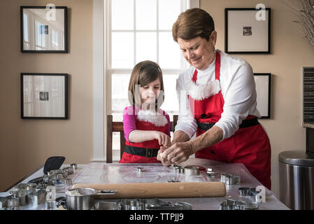 La nipote aiutando la nonna nel rendere gingerbread cookies a casa Foto Stock