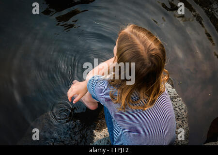 Vista aerea della ragazza seduta sulla roccia nel lago Foto Stock