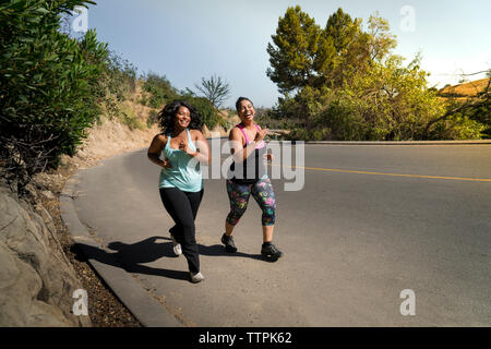 Happy amici di sesso femminile jogging sulla strada durante la giornata di sole Foto Stock