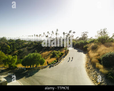 Angolo di alta vista di amici di sesso femminile jogging sulla strada contro il cielo chiaro Foto Stock