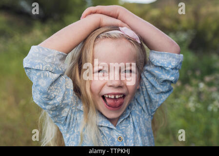 Ritratto di felice ragazza con le mani sulla testa in piedi in posizione di parcheggio Foto Stock