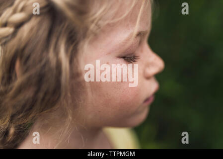 Vista laterale di close-up di ragazza con gli occhi chiusi in piedi nella foresta Foto Stock