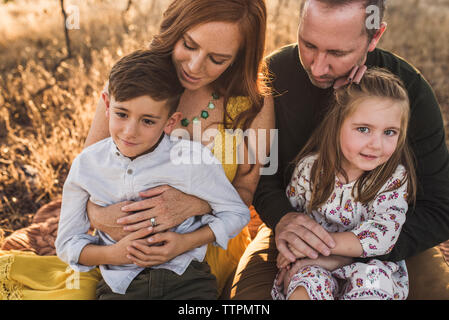 Close up della famiglia coccole insieme su una coperta nel campo della California Foto Stock