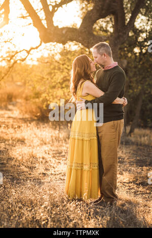 Donna abbracciando il marito mentre nel campo della California durante il tramonto Foto Stock