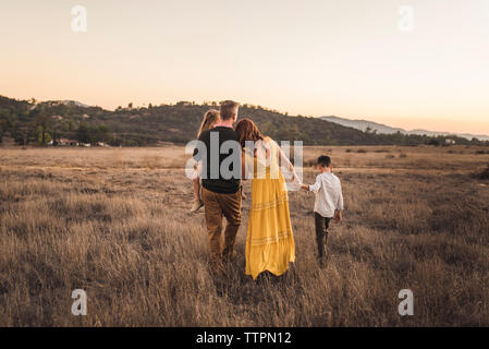 Famiglia giovane tenendo le mani durante la camminata di distanza nel campo della California Foto Stock