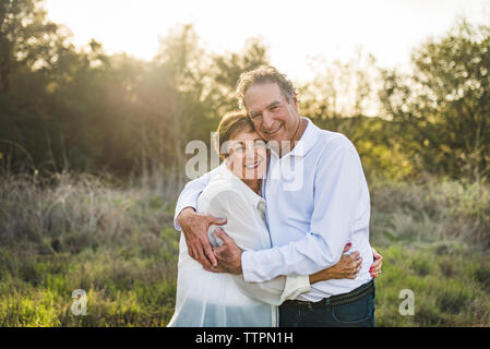 Coppia senior abbracciando e sorridente al di fuori in controluce Foto Stock