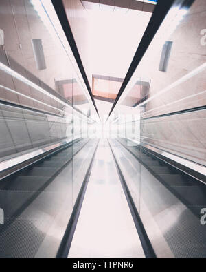 Basso angolo vista di escalator riflettendo su vetro Foto Stock