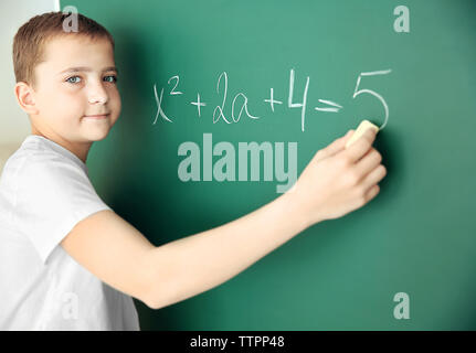 Carino schoolboy scrivere sulla lavagna Foto Stock