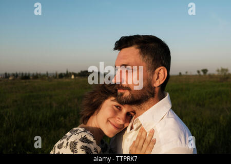 Ritratto di donna in stato di gravidanza che comprenda l'uomo sul campo contro il cielo chiaro Foto Stock