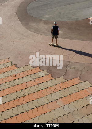 Elevato angolo di visione dell'uomo lo skateboard su strada in città durante la giornata di sole Foto Stock