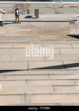 Elevato angolo di visione dell'uomo lo skateboard su strada in città durante la giornata di sole Foto Stock