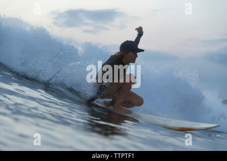 Donna surf sul mare contro il cielo durante il tramonto Foto Stock