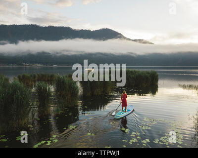 Una femmina paddleboarding su un lago Foto Stock