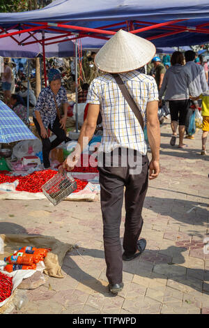 Uomo che cammina attraverso il mercato con lo scoiattolo in trappola, Bac Ha, Lao Cai Provincia, Vietnam, Asia Foto Stock