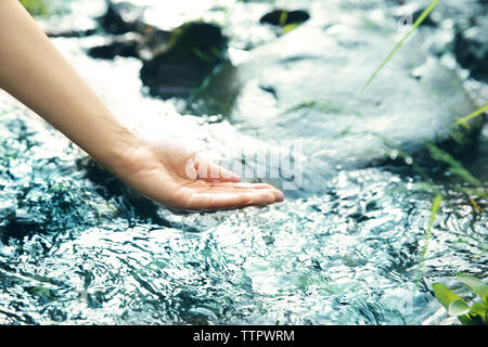 Donna versando acqua in mano Foto Stock