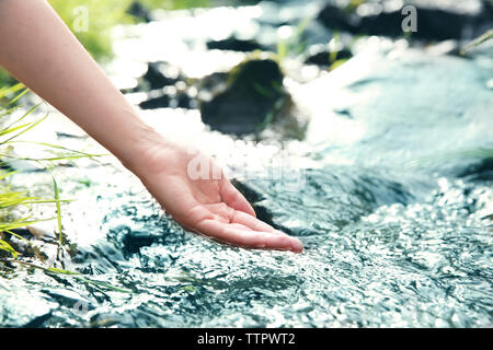Donna versando acqua in mano Foto Stock