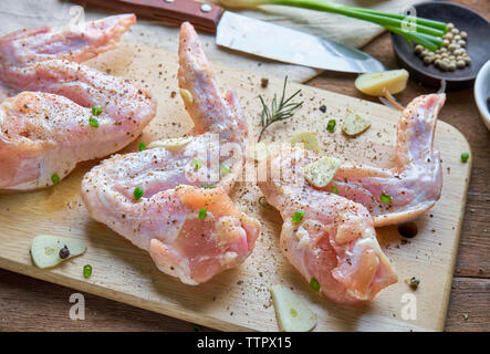 Angolo di alta vista della carne di pollo con spice sul tagliere a tavola Foto Stock