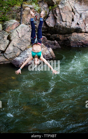 Donna appeso sulla corda mentre slacklining oltre il fiume Foto Stock