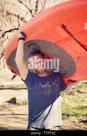 Ritratto di uomo felice paddleboard portante nella foresta Foto Stock