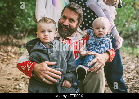 Ritratto di uomo e i bambini contro la famiglia sul campo al park Foto Stock