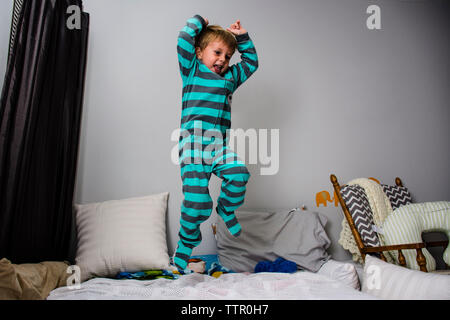 Giocoso ragazzo di saltare sul letto di casa Foto Stock
