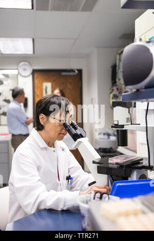 Femmina senior scientist usando microscopio in laboratorio Foto Stock