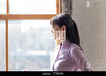 Riflessivo imprenditrice guardando attraverso la finestrella in office Foto Stock