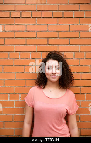 Ritratto di fiducioso imprenditrice in piedi contro un muro di mattoni Foto Stock