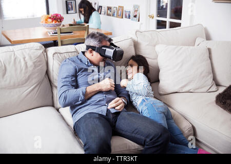 Giocoso padre indossa la realtà virtuale simulatore mentre giocando con la figlia a casa Foto Stock