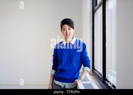 Ritratto di fiducioso imprenditrice in piedi dalla finestra nel nuovo ufficio Foto Stock