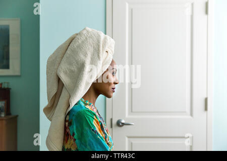 Vista laterale della donna che guarda lontano mentre indossa l'asciugamano sulla testa Foto Stock