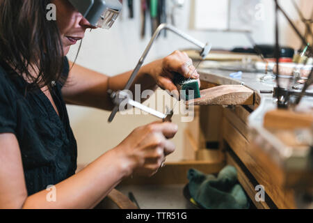 Sezione mediana di artigiani femmina apparecchiatura di taglio con handsaw sulla tavola in officina Foto Stock