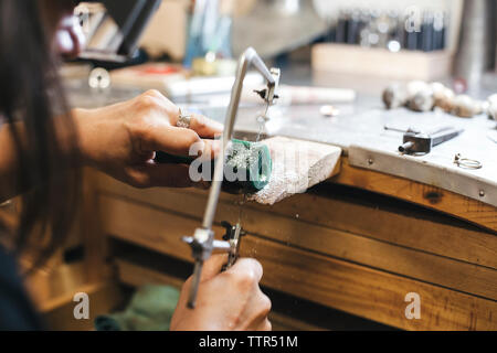 Tagliate le mani di artigiani femmina apparecchiatura di taglio con handsaw sulla tavola in officina Foto Stock