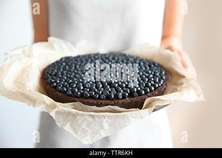 Donna che mantiene torta al cioccolato con frutti di bosco Foto Stock