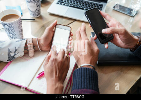 Immagine ritagliata della gente di affari utilizzando i telefoni cellulari in office Foto Stock