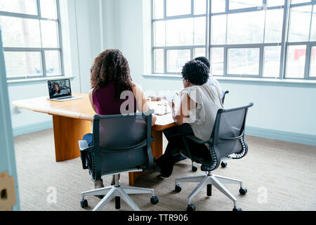 le persone d'affari possono videoconferenze con un computer portatile e una donna d'affari seduto in sala riunioni Foto Stock