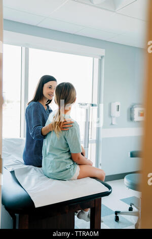 Madre figlia consolante mentre è seduto sul lettino visto attraverso la porta Foto Stock