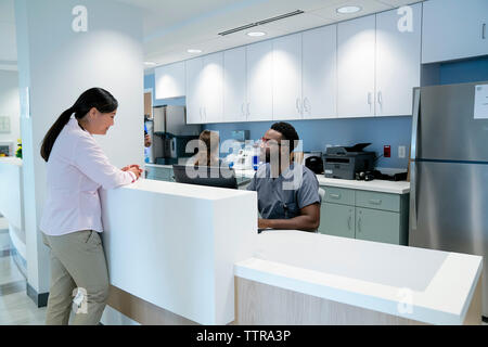 Medico di parlare con un collega mentre collega femmina lavorando in background Foto Stock
