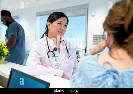 Medico guardando il collega di sesso maschile con un collega in background Foto Stock