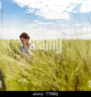 Donna coltivati nel campo di grano contro il cielo chiaro Foto Stock