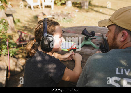 Angolo di alta vista di felice figlia indossando le cuffie mentre guardando il padre Foto Stock