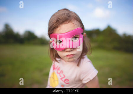 Close-up verticale di una ragazza che indossa la maschera mentre in piedi contro il cielo a park Foto Stock