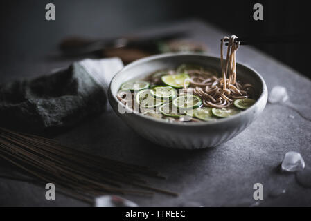 Close-up di Soba Noodles nella ciotola con bacchette sul banco di cucina Foto Stock