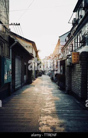 Strada vuota nel mezzo di edifici contro il cielo chiaro durante il tramonto Foto Stock