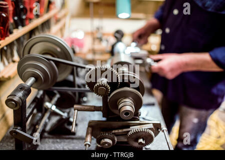 Sezione mediana del lavoratore funzionamento di macchinari in officina Foto Stock