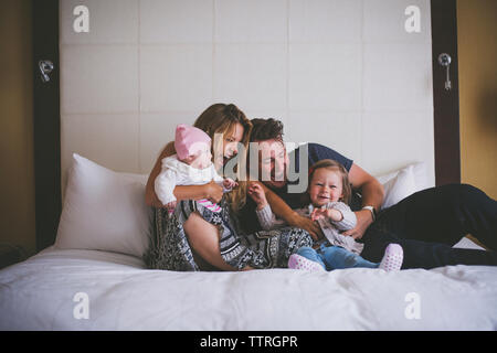 La famiglia felice avendo divertimento su letto di casa Foto Stock