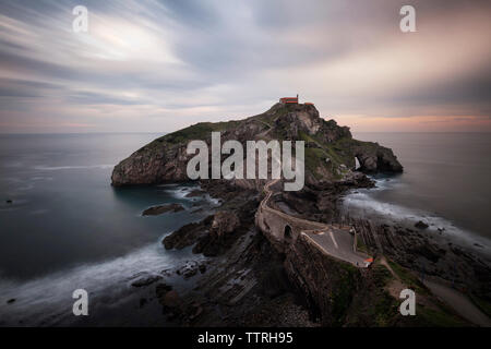 Vista panoramica di San Juan de Gaztelugatxe in mezzo al mare contro il cielo nuvoloso durante il tramonto Foto Stock