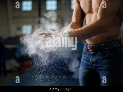 Sezione mediana del ginnasta maschio applicando polvere di gesso sulle mani Foto Stock