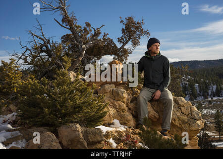 L'uomo con il cane seduto sulle formazioni rocciose contro il cielo al Parco Nazionale di Bryce Canyon Foto Stock